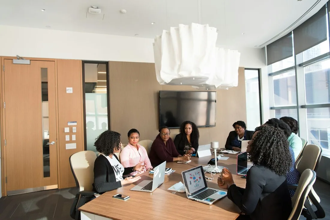 Colleagues discuss work around a table in a modern meeting room.
